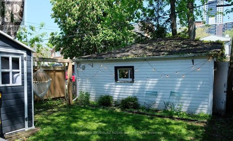 A small white shed with a window and a door is surrounded by a green lawn.