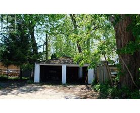A garage is surrounded by trees and appears to be unused.
