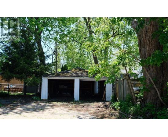 A garage is surrounded by trees and appears to be unused.