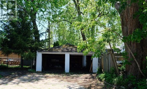 A garage is surrounded by trees and appears to be unused.