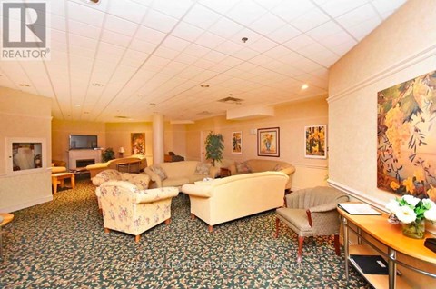A living room with a carpet and a painting on the wall.