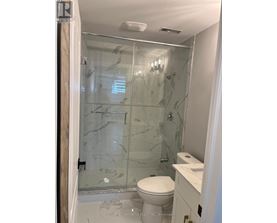 A bathroom with a glass shower door and a toilet.