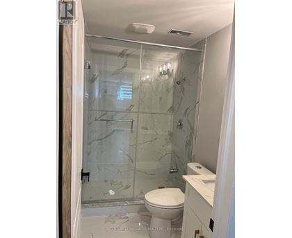 A bathroom with a glass shower door and a toilet.