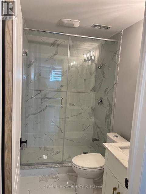 A bathroom with a glass shower door and a toilet.