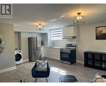A modern kitchen with a blue chair and a fridge.