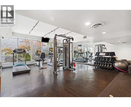 A gym with a variety of equipment including a treadmill, weights, and a rowing machine.