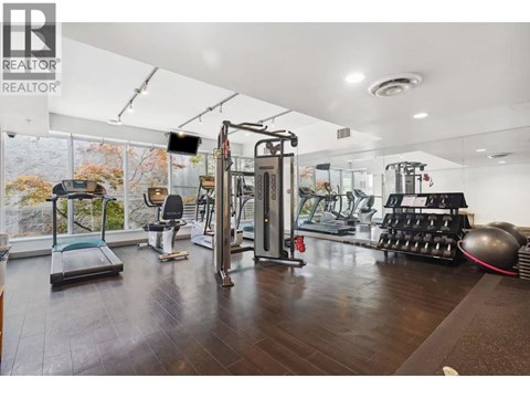 A gym with a variety of equipment including a treadmill, weights, and a rowing machine.