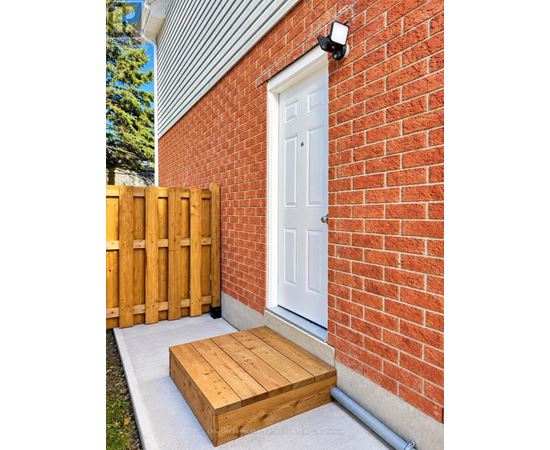 A white door is on a red brick wall with a wooden fence and a wooden box in front of it.