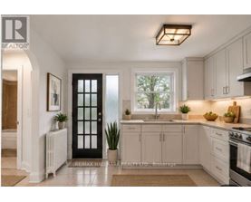 A well-lit kitchen with white cabinets and a black door.