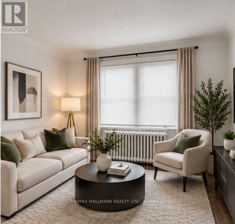 A living room with a white sofa, a green cushion, a black coffee table, a white chair, a small potted plant, and a framed picture on the wall.