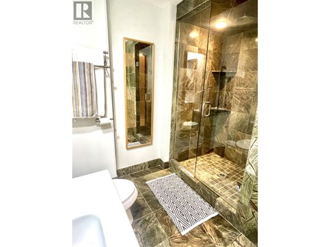A bathroom with a glass shower stall and a toilet.