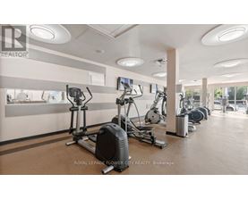 A gym with exercise equipment and a wall of windows.
