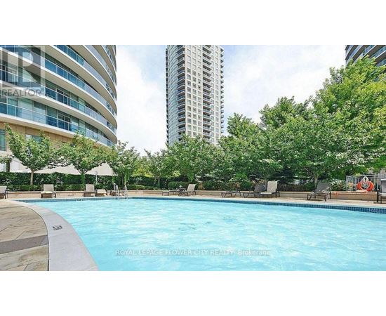 A pool surrounded by trees and chairs with a building in the background.