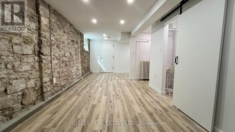 A hallway with a stone wall on the left and wooden flooring.