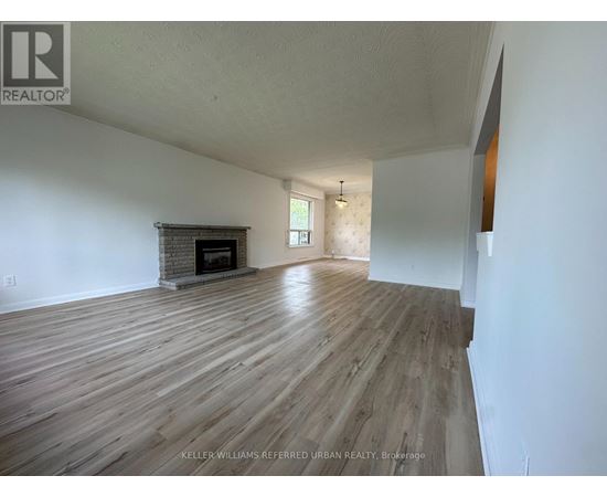 A spacious room with wooden flooring and a fireplace.