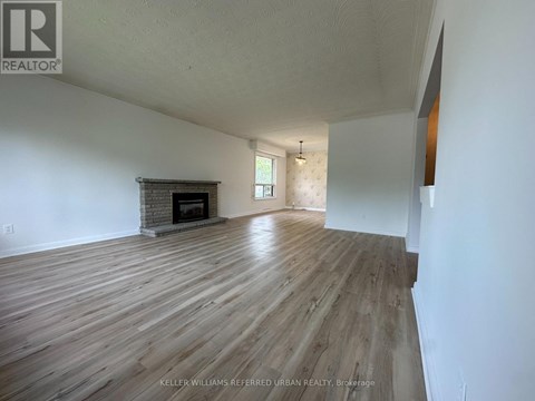A spacious room with wooden flooring and a fireplace.