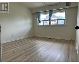 A room with a window and a wooden floor.