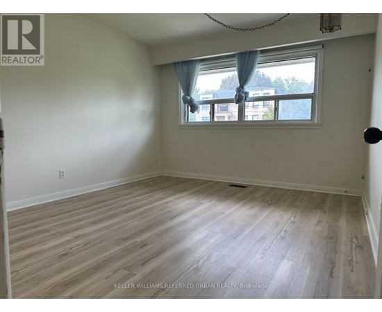 A room with a window and a wooden floor.