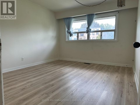 A room with a window and a wooden floor.