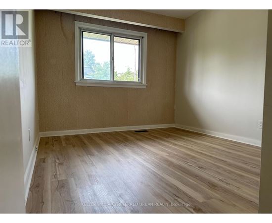 A room with a window and wooden flooring.