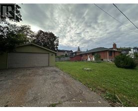 A residential area with houses and a dirt driveway.