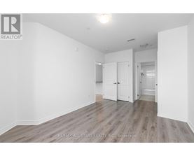 A spacious room with wooden flooring and white walls.