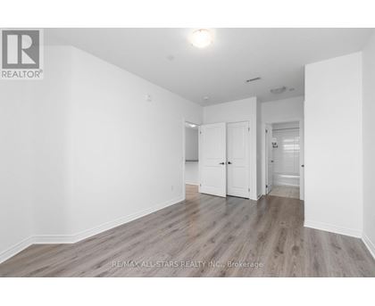 A spacious room with wooden flooring and white walls.