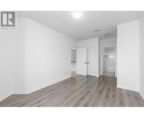 A spacious room with wooden flooring and white walls.