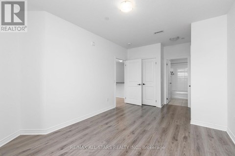 A spacious room with wooden flooring and white walls.
