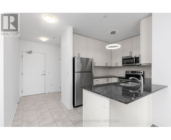 A kitchen with white cabinets and a black countertop.