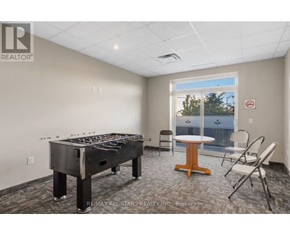 A room with a pool table and chairs.