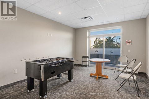 A room with a pool table and chairs.