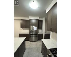 A kitchen with a stainless steel refrigerator and dark brown cabinets.