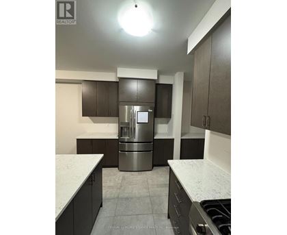 A kitchen with a stainless steel refrigerator and dark brown cabinets.