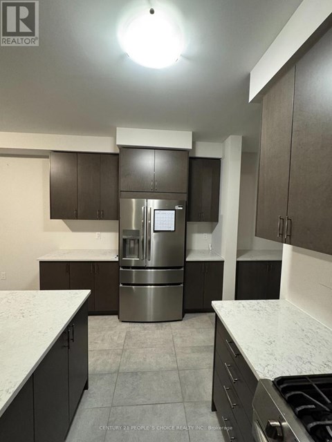 A kitchen with a stainless steel refrigerator and dark brown cabinets.