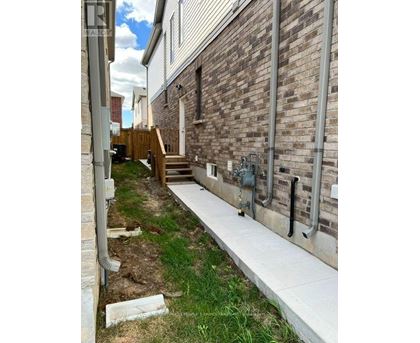 A brick building with a white wall and a concrete walkway.