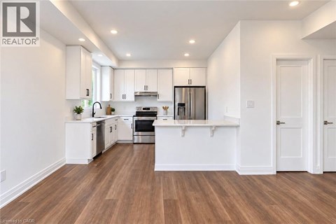 A modern kitchen with white cabinets and wooden floors.