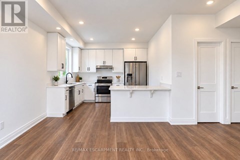 A modern kitchen with white cabinets and a wooden floor.