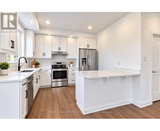 A white kitchen with a refrigerator, oven, and sink.