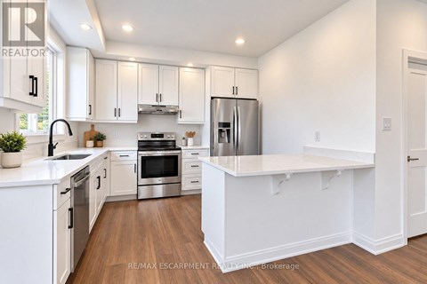 A white kitchen with a refrigerator, oven, and sink.