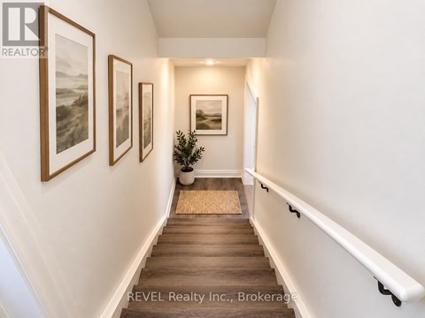 A hallway with a potted plant and pictures on the wall.
