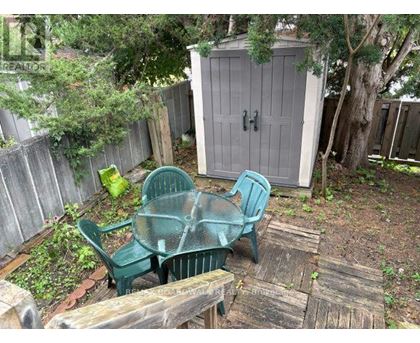 A backyard with a wooden table and two green chairs.