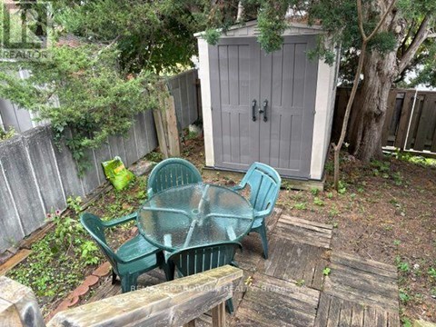 A backyard with a wooden table and two green chairs.