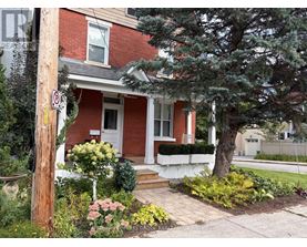 A red brick house with a white door and a no parking sign on a pole.