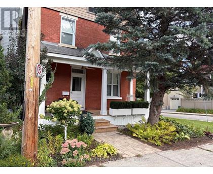 A red brick house with a white door and a no parking sign on a pole.