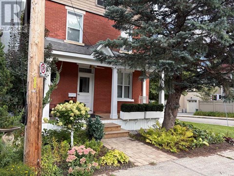 A red brick house with a white door and a no parking sign on a pole.