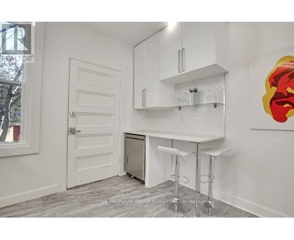 A white kitchen with a bar stool and a painting on the wall.