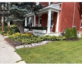 A red brick house with a white porch and a sign that says REALTOR.