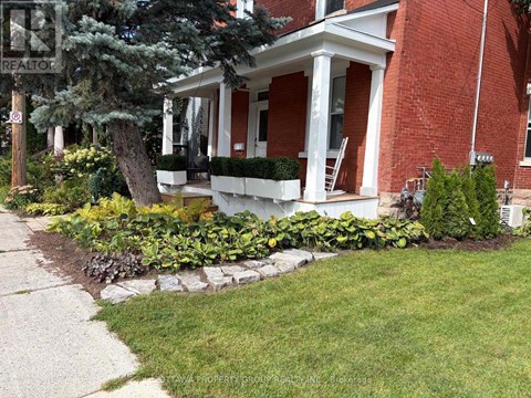 A red brick house with a white porch and a sign that says REALTOR.