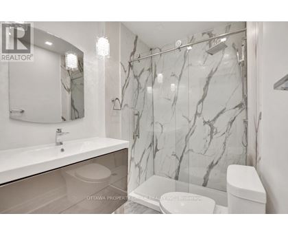 A bathroom with marble wallpaper and a glass shower door.